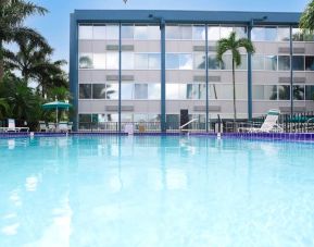 Relaxing outdoor pool with lounge area at EnVision Hotel Miami International Airport.