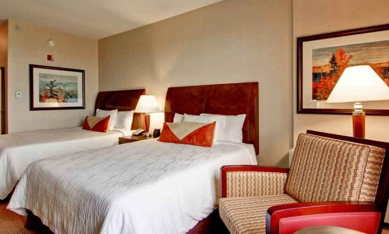 2 queen beds in a bright room with TV screen and sofa at the Hilton Garden Inn Calgary Airport.