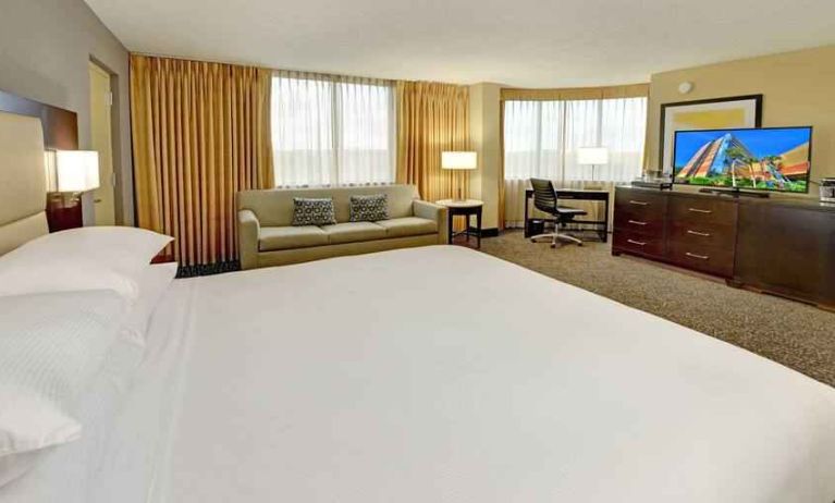 King room with king bed, TV screen, desk and sofa at the Hilton Orlando-Altamonte Springs.