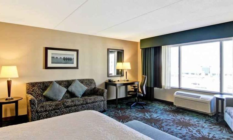 Hotel room with king size bed, living room and window view at the Hampton Inn by Hilton Toronto Airport Corporate Centre.