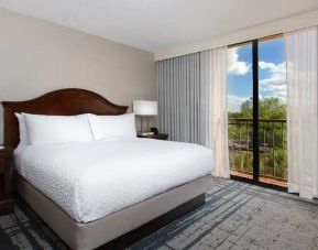 Bright king room with king bed and window at the Embassy Suites by Hilton Orlando International Drive Convention Center.