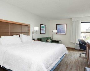 King room with king bed, TV screen, sofa bed and desk at the Hampton Inn Orlando International Drive Convention Center.
