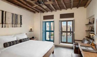 Bright room with king size bed, desk and windows at the Al Seef Heritage Hotel Dubai, Curio Collection by Hilton.