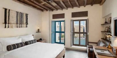 Bright room with king size bed, desk and windows at the Al Seef Heritage Hotel Dubai, Curio Collection by Hilton.