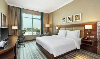 Comfortable King room with king bed, desk, tv and living room area at the Hilton Garden Inn Dubai Al Mina