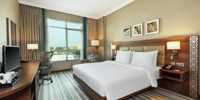 Comfortable King room with king bed, desk, tv and living room area at the Hilton Garden Inn Dubai Al Mina