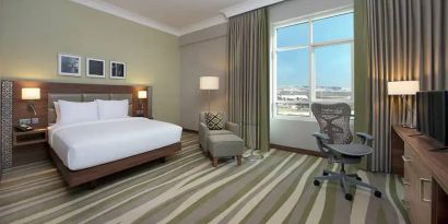 Large hotel room with king-size bed, great view of the city and spacious work area.