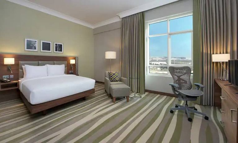 Large hotel room with king-size bed, great view of the city and spacious work area.