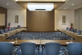 Spacious conference room with tables and chairs and a big wall for screenings at the Hilton Garden Inn Dubai Al Mina