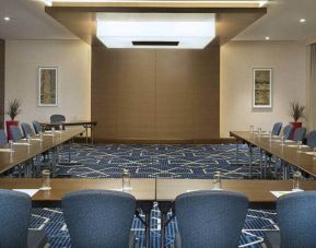 Spacious conference room with tables and chairs and a big wall for screenings at the Hilton Garden Inn Dubai Al Mina