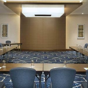 Spacious conference room with tables and chairs and a big wall for screenings at the Hilton Garden Inn Dubai Al Mina