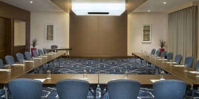 Spacious conference room with tables and chairs and a big wall for screenings at the Hilton Garden Inn Dubai Al Mina