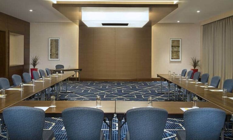 Spacious conference room with tables and chairs and a big wall for screenings at the Hilton Garden Inn Dubai Al Mina