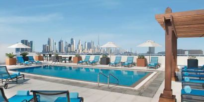 Beautiful outdoor pool with deck and pool chairs at the Hilton Garden Inn Dubai Al Mina