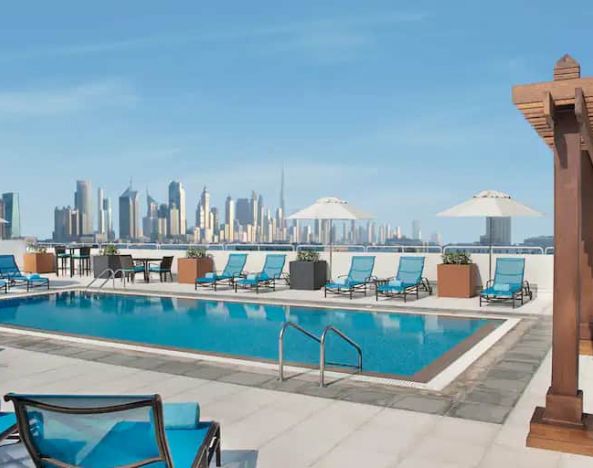 Beautiful outdoor pool with deck and pool chairs at the Hilton Garden Inn Dubai Al Mina
