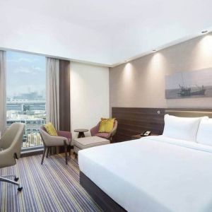 Spacious room with queen bed, desk and chair area at the Hampton Dubai Airport