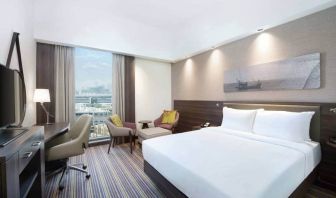 Spacious room with queen bed, desk and chair area at the Hampton Dubai Airport