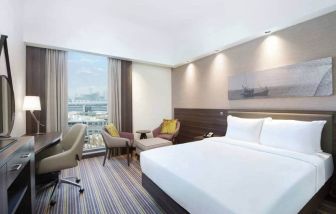 Spacious room with queen bed, desk and chair area at the Hampton Dubai Airport