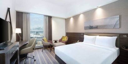 Spacious room with queen bed, desk and chair area at the Hampton Dubai Airport