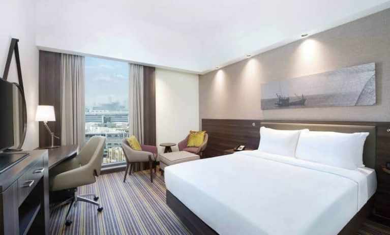 Spacious room with queen bed, desk and chair area at the Hampton Dubai Airport