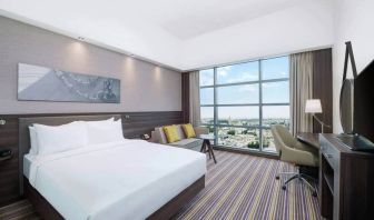 Spacious room with queen bed, pull out sofa, desk and chair area at the Hampton Dubai Airport