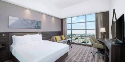 Spacious room with queen bed, pull out sofa, desk and chair area at the Hampton Dubai Airport