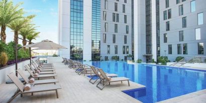 Beautiful outdoor pool with pool chairs at the Hampton Dubai Airport