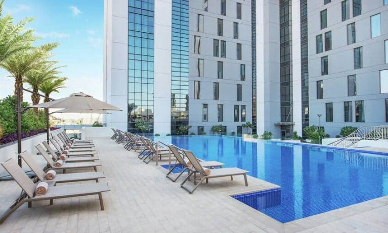 Beautiful outdoor pool with pool chairs at the Hampton Dubai Airport