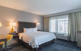 King bed with work desk and natural light at Hampton Inn Chicago North-Loyola Station.