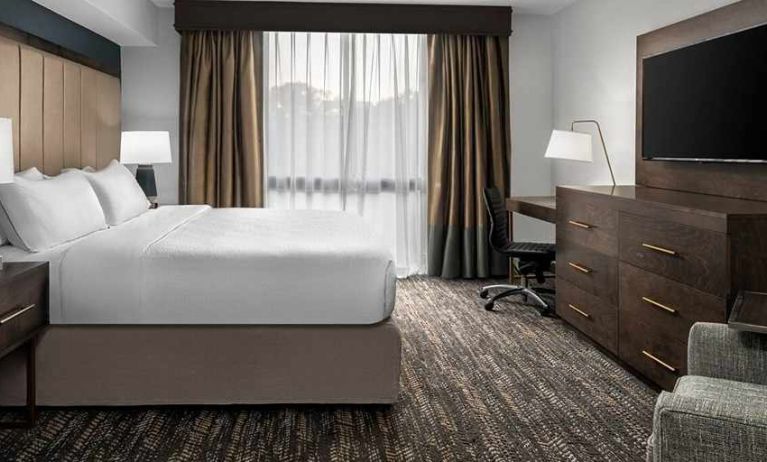 Comfortable king bed with TV and work area at Embassy Suites by Hilton Nashville Airport.