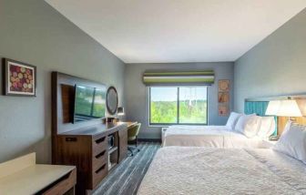 Double queen bedroom with desk, window and TV screen at the at the Hampton Inn Madison, OH.