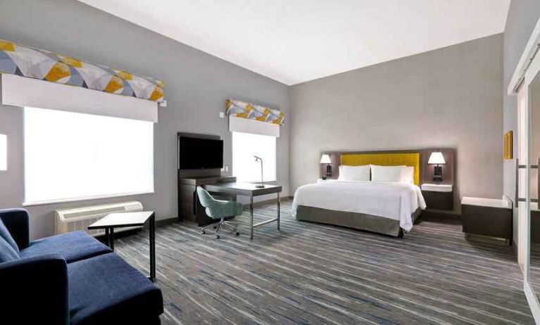 Bright and spacious king guestroom with desk and sofa at the Hampton Inn & Suites Houston East Beltway 8.