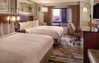 Stylish bedroom with two queen size beds, desk and TV screen at the Hilton Denver City Center.