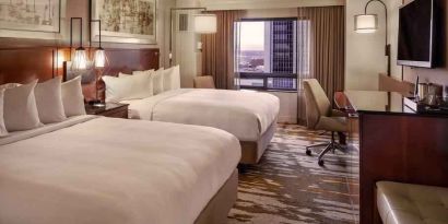 Stylish bedroom with two queen size beds, desk and TV screen at the Hilton Denver City Center.