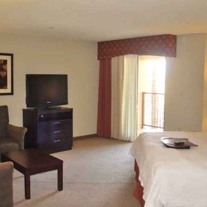 delux king-sized bed with lounge area and TV at Hampton Inn & Suites Phoenix/Gilbert, AZ.