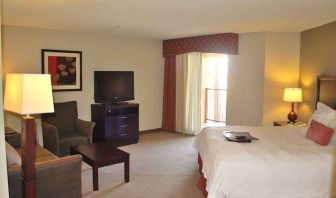 delux king-sized bed with lounge area and TV at Hampton Inn & Suites Phoenix/Gilbert, AZ.