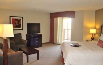 delux king-sized bed with lounge area and TV at Hampton Inn & Suites Phoenix/Gilbert, AZ.