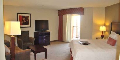 delux king-sized bed with lounge area and TV at Hampton Inn & Suites Phoenix/Gilbert, AZ.