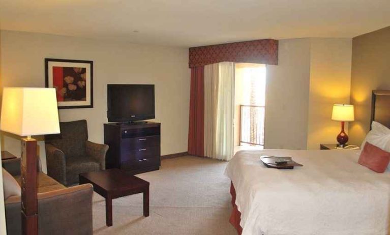 delux king-sized bed with lounge area and TV at Hampton Inn & Suites Phoenix/Gilbert, AZ.