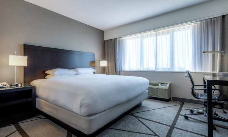 king-sized bed equipped with TV and work desk and with natural light at DoubleTree by Hilton Los Angeles - Norwalk.