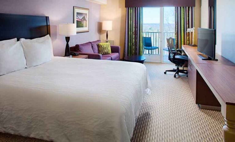 Comfortable king size bed, sofa and desk in a hotel room at the Hilton Garden Inn Hartford North/Bradley Intl Airport.