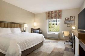 bright-lit king-sized bed with TV and work desk at Hampton Inn Salt Lake City Cottonwood.