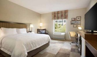 bright-lit king-sized bed with TV and work desk at Hampton Inn Salt Lake City Cottonwood.