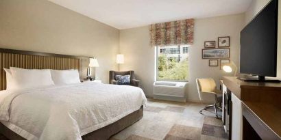 bright-lit king-sized bed with TV and work desk at Hampton Inn Salt Lake City Cottonwood.