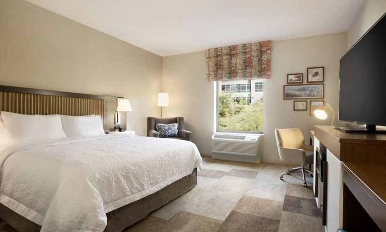 bright-lit king-sized bed with TV and work desk at Hampton Inn Salt Lake City Cottonwood.