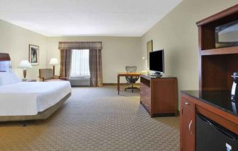 Spacious and bright king guestroom with TV and desk at the Hilton Garden Inn Clarksburg.