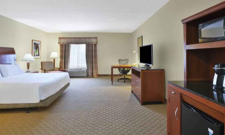 Spacious and bright king guestroom with TV and desk at the Hilton Garden Inn Clarksburg.