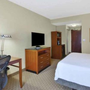 King size bed, desk and TV screen in a hotel room at the Hilton Garden Inn Clarksburg.