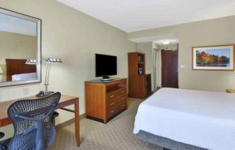 King size bed, desk and TV screen in a hotel room at the Hilton Garden Inn Clarksburg.