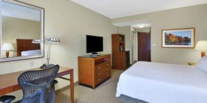 King size bed, desk and TV screen in a hotel room at the Hilton Garden Inn Clarksburg.